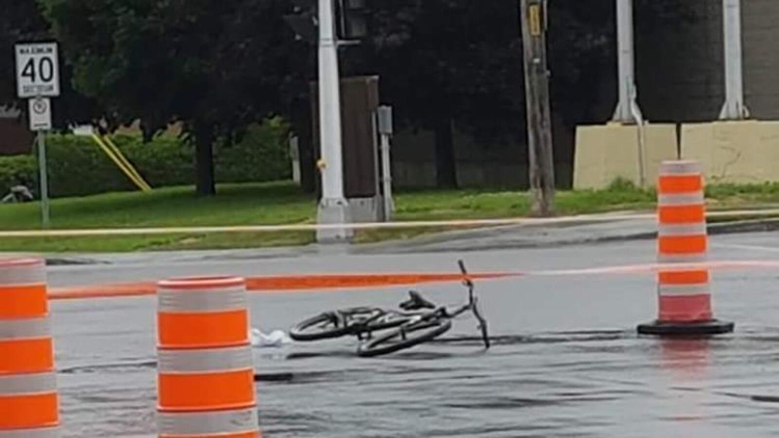 Une bicyclette étendue sur la chaussée entourée d'un ruban orange.