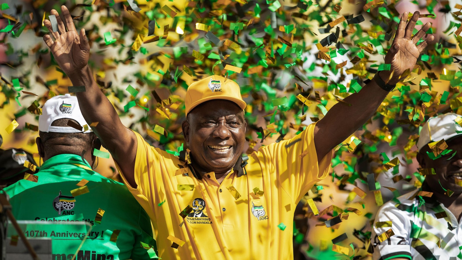 Cyril Ramaphosa, vêtu en jaune, lève les bras au ciel.
