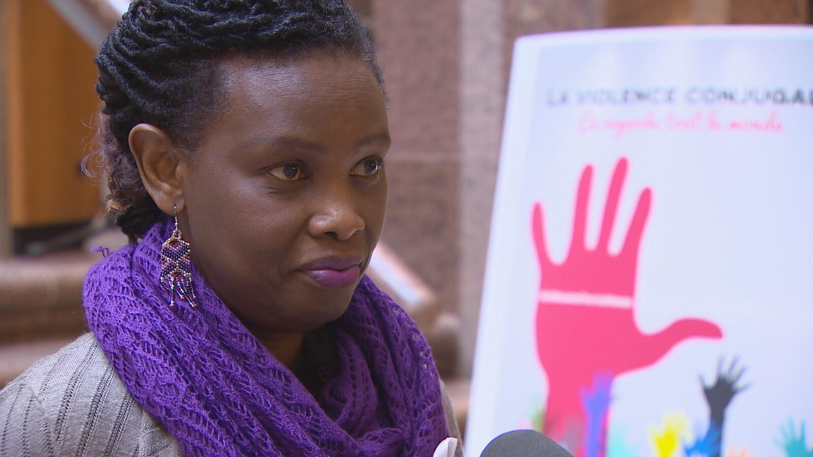 Dada Gasirabo devant une affiche de la campagne de sensibilisation contre la violence faite aux femmes.