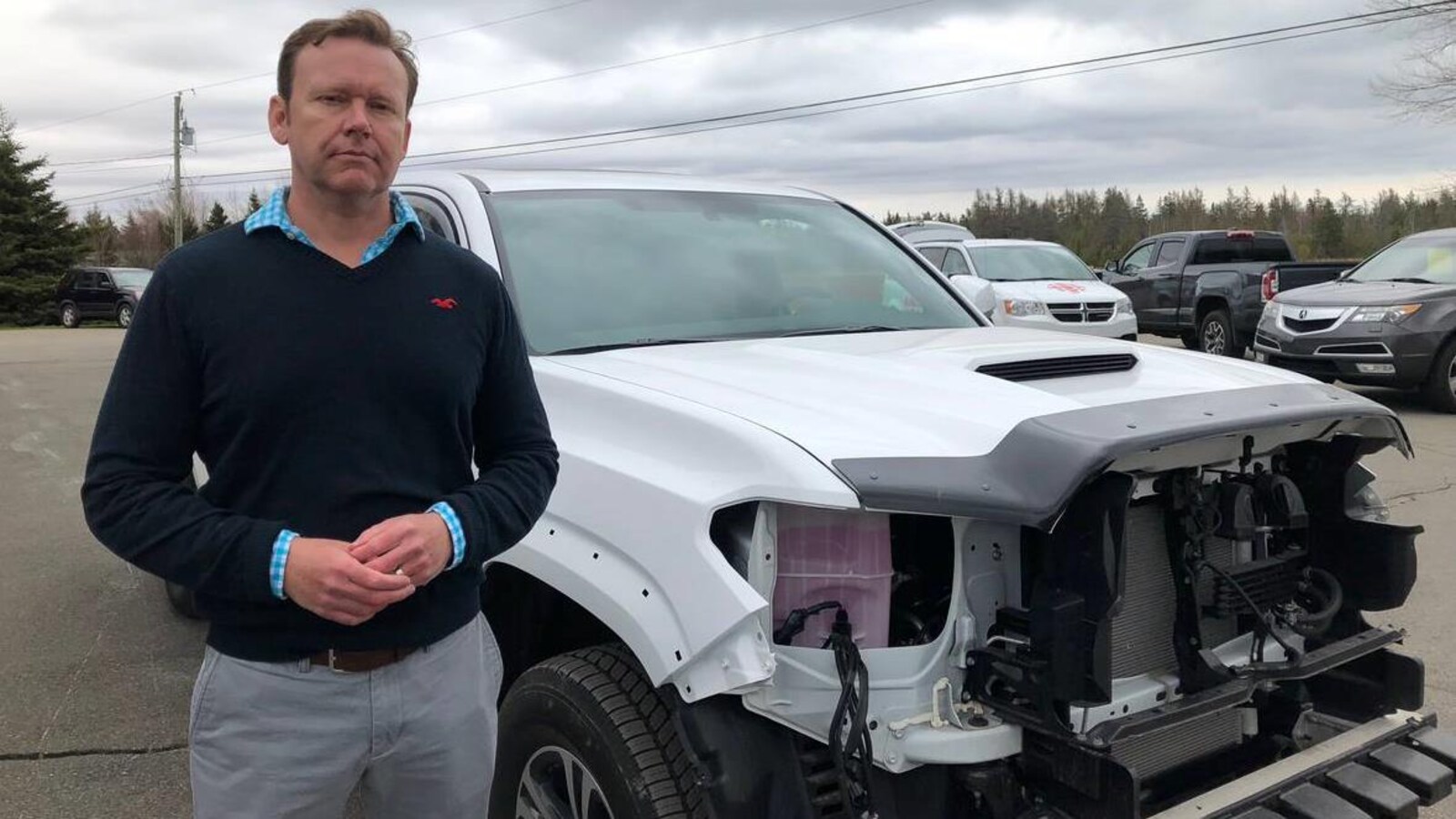 Sam Dalton debout devant sa camionnette qui n'a plus de phares ni de radiateur