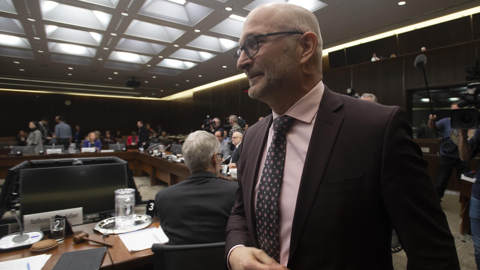 David Lametti marche dans la salle du comité. Des membres sont assis autour d'une table.