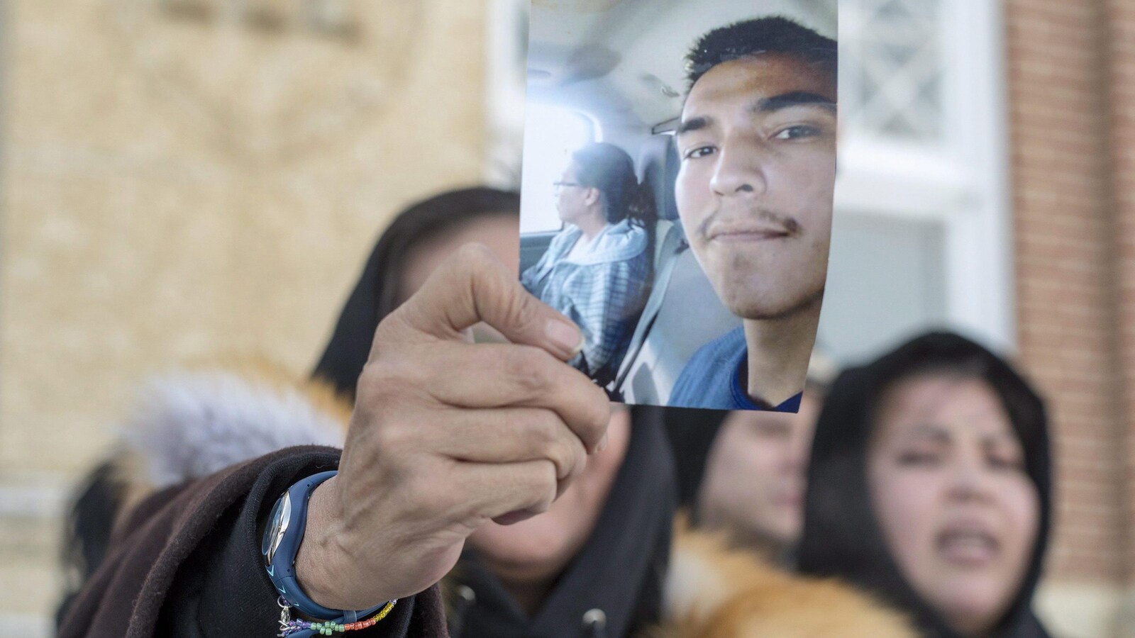 Une femme montre une photo de Colten Boushie devant une foule.