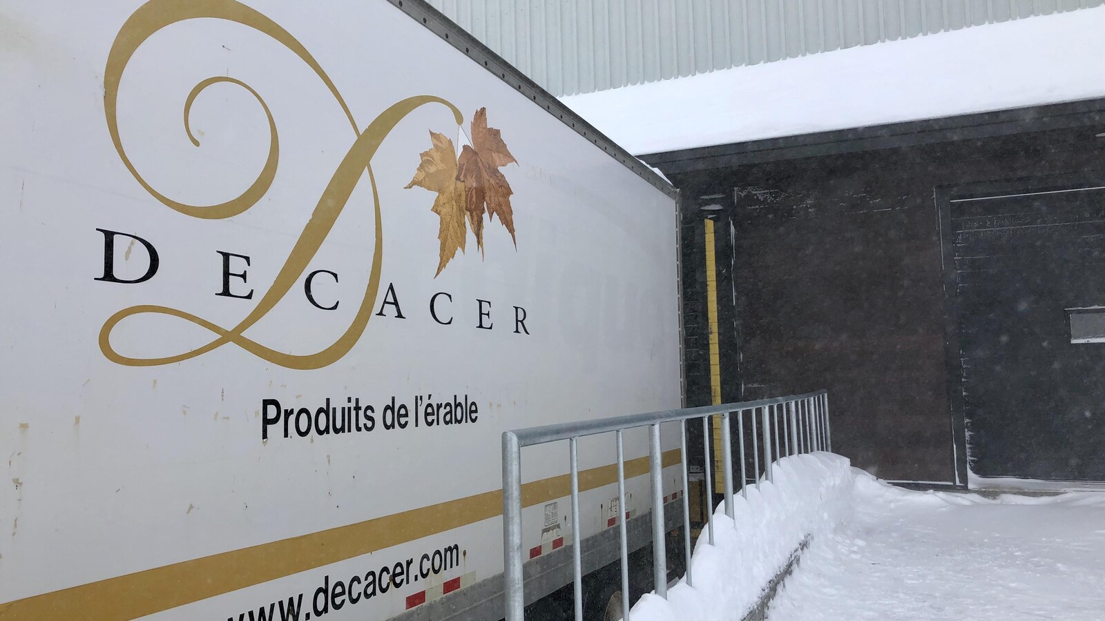 Remorque d'un camion reculé dans la porte d'un bâtiment industriel.