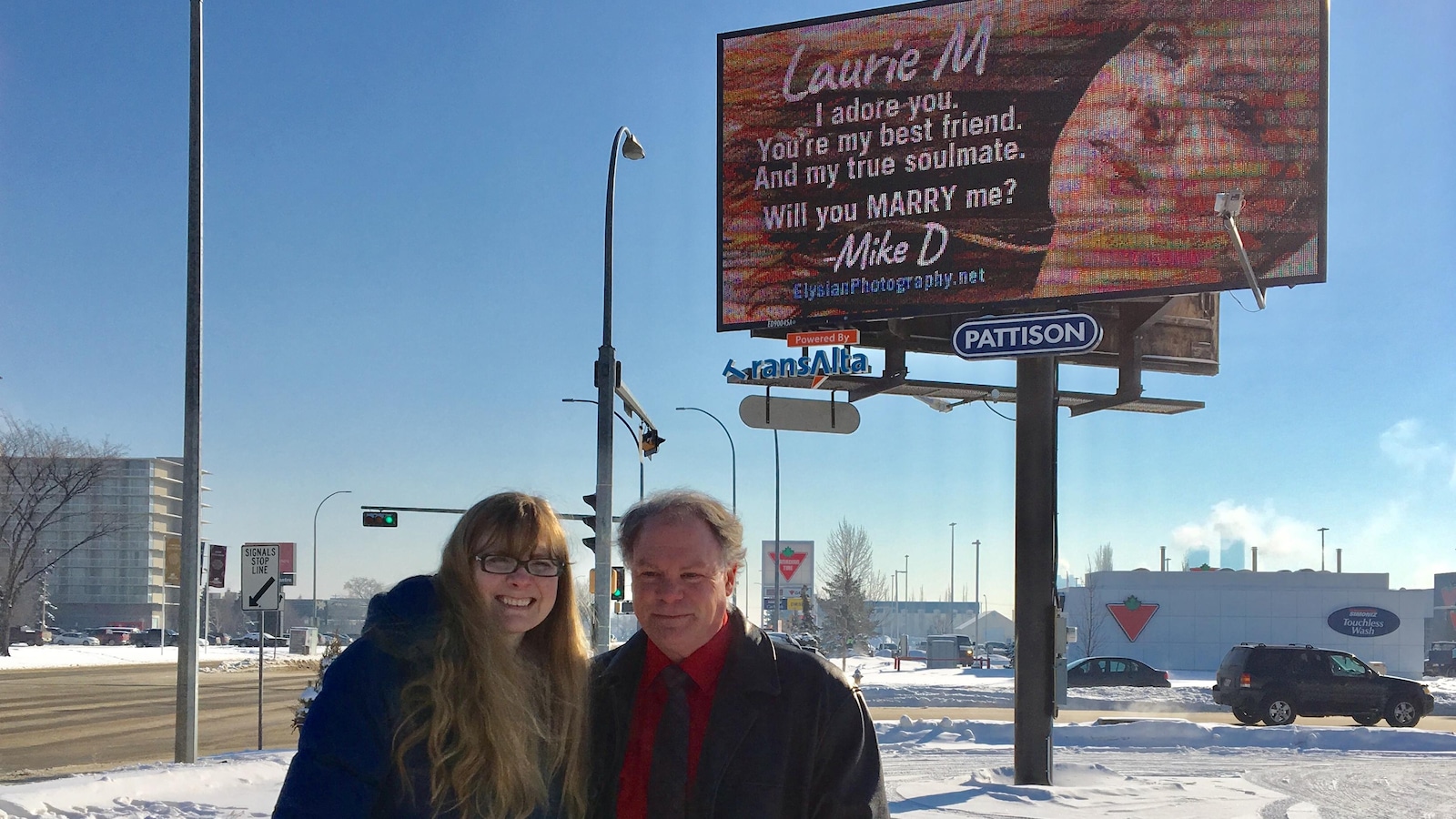 Un couple devant un panneau publicitaire dans un stationnement vide enneigé