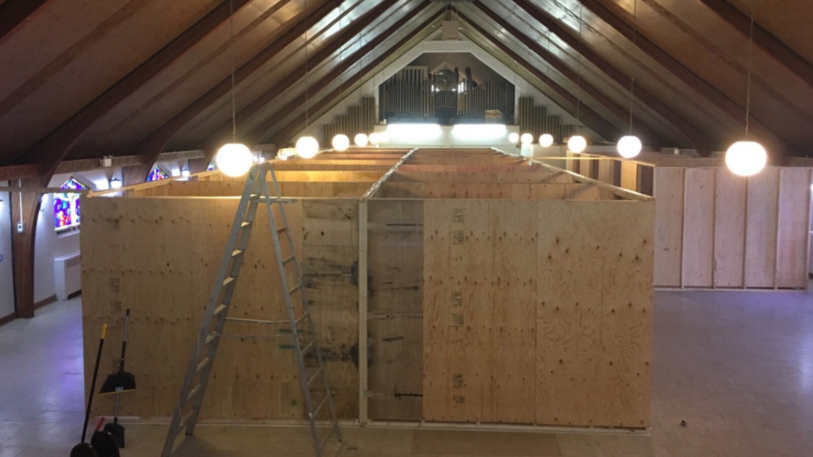 De larges panneaux de contreplaqué délimitent des chambres individuelles de fortune dans une église.
