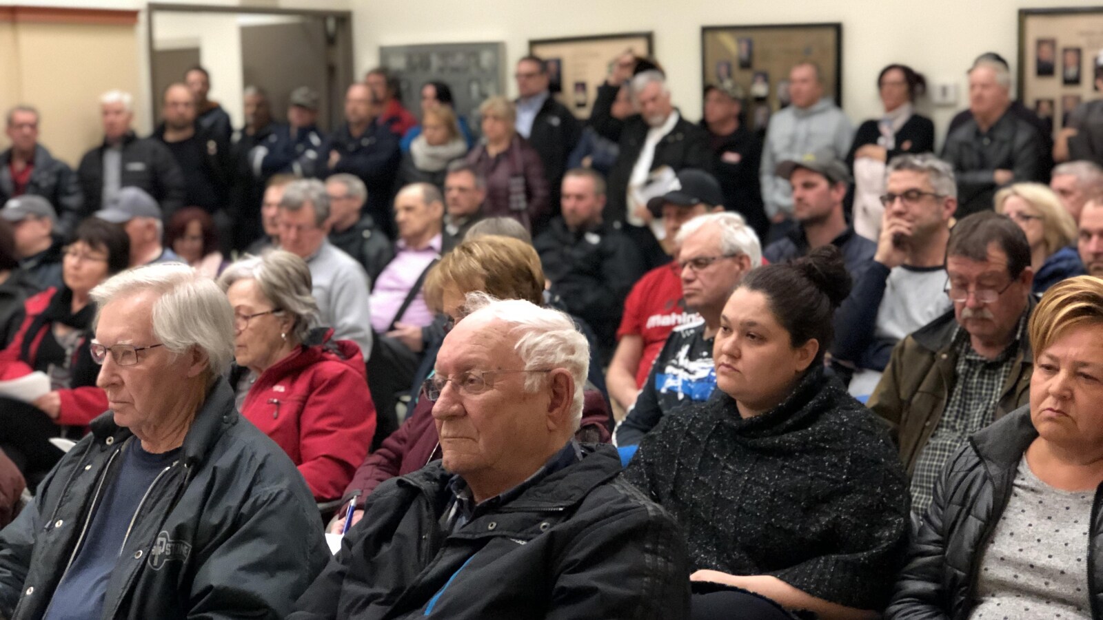 Des gens mécontents assis dans la salle du conseil de Saint-Ambroise.