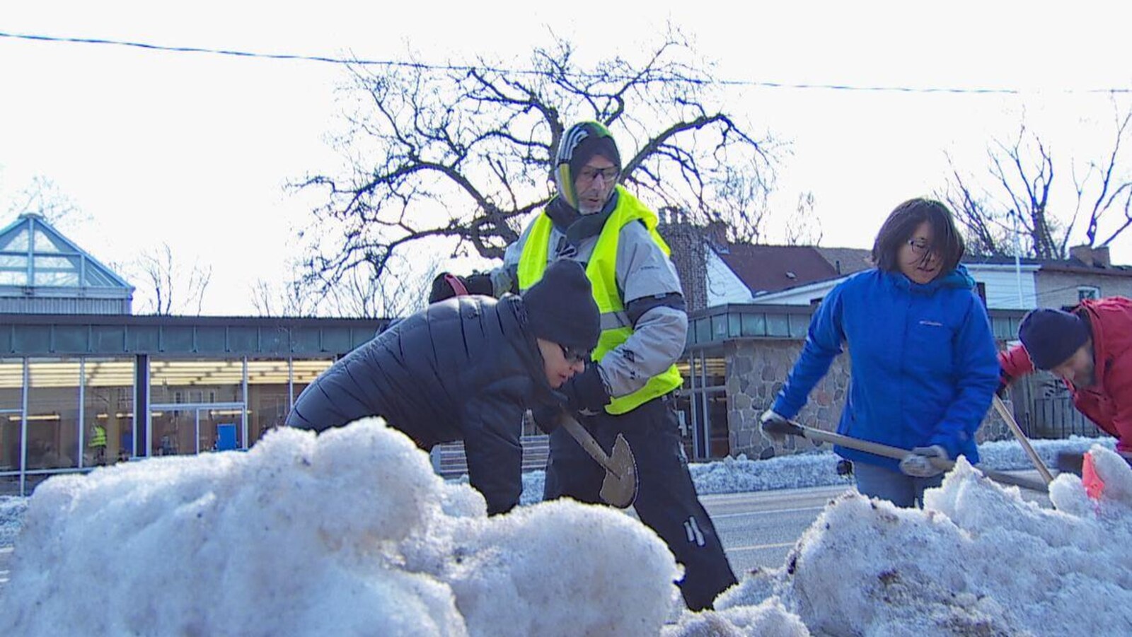 Trois personnes avec des pelles dans un banc de neige