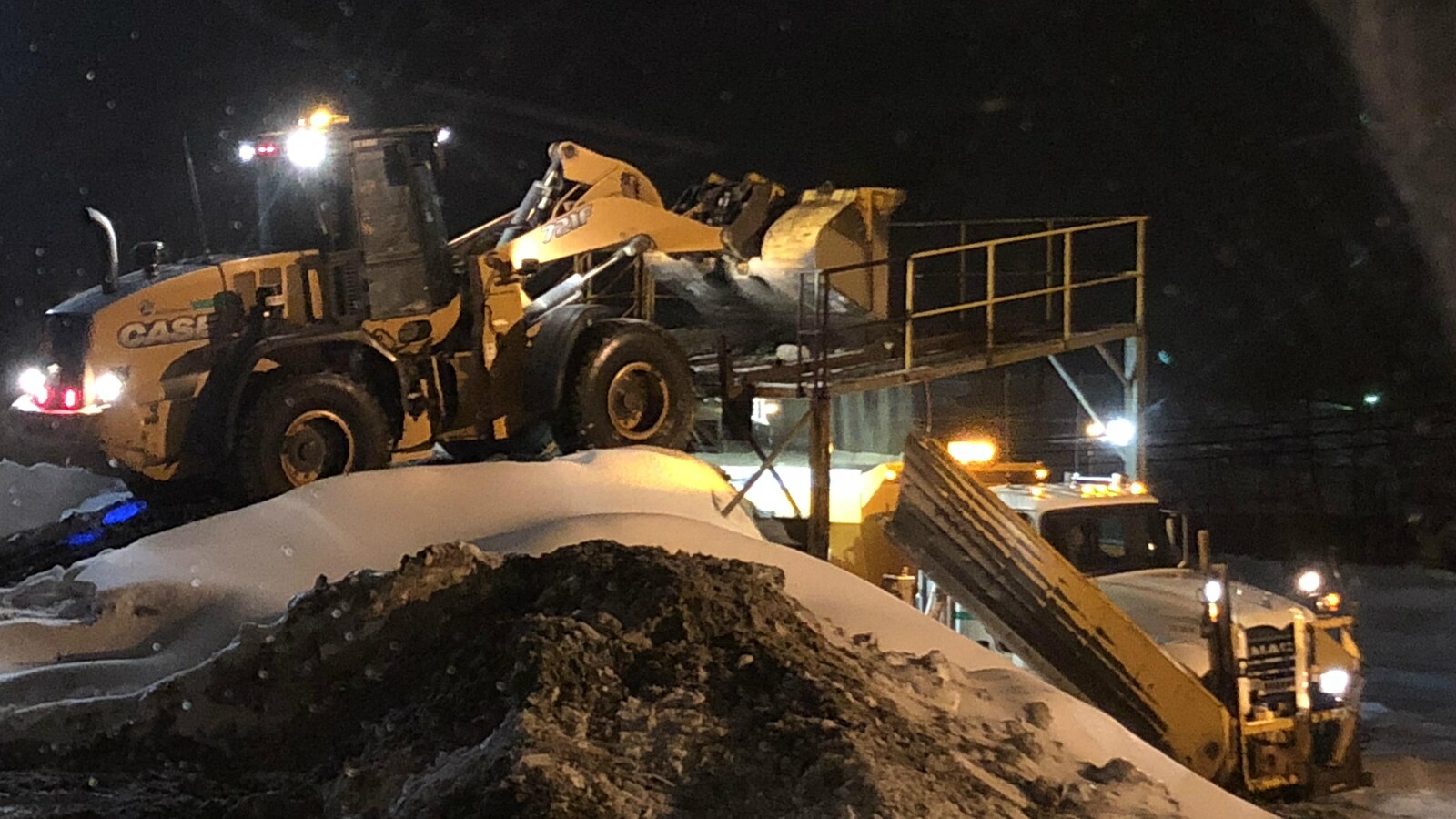 Deux camions de déneigement travaillent de nuit.