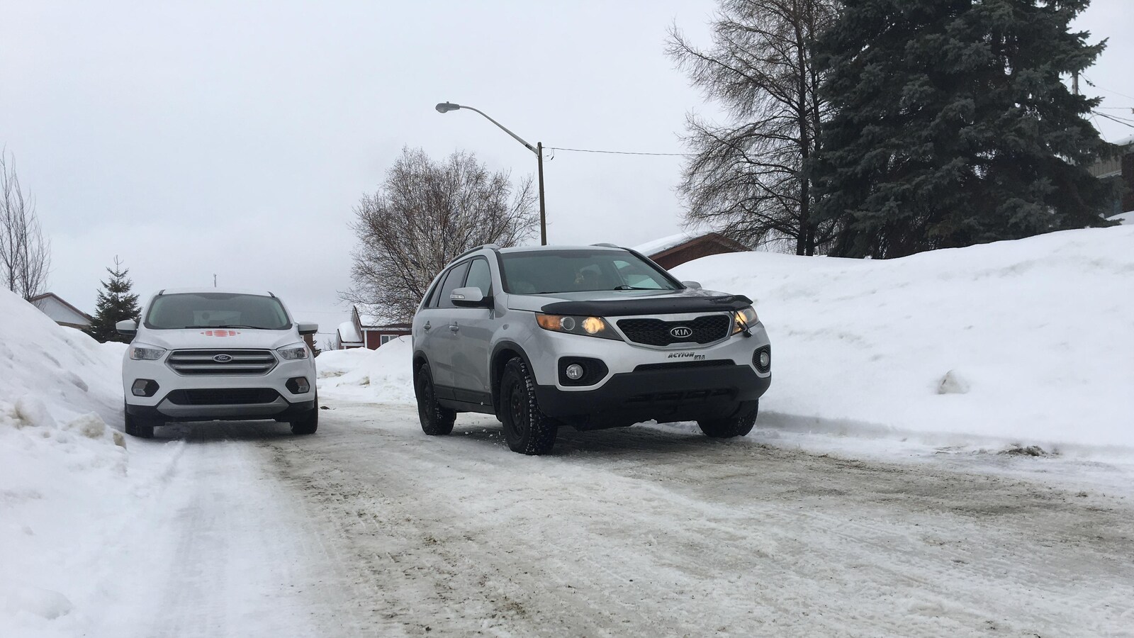 Une voiture circule dans la voie opposée pour contourner un véhicule stationné dans une rue résidentielle.