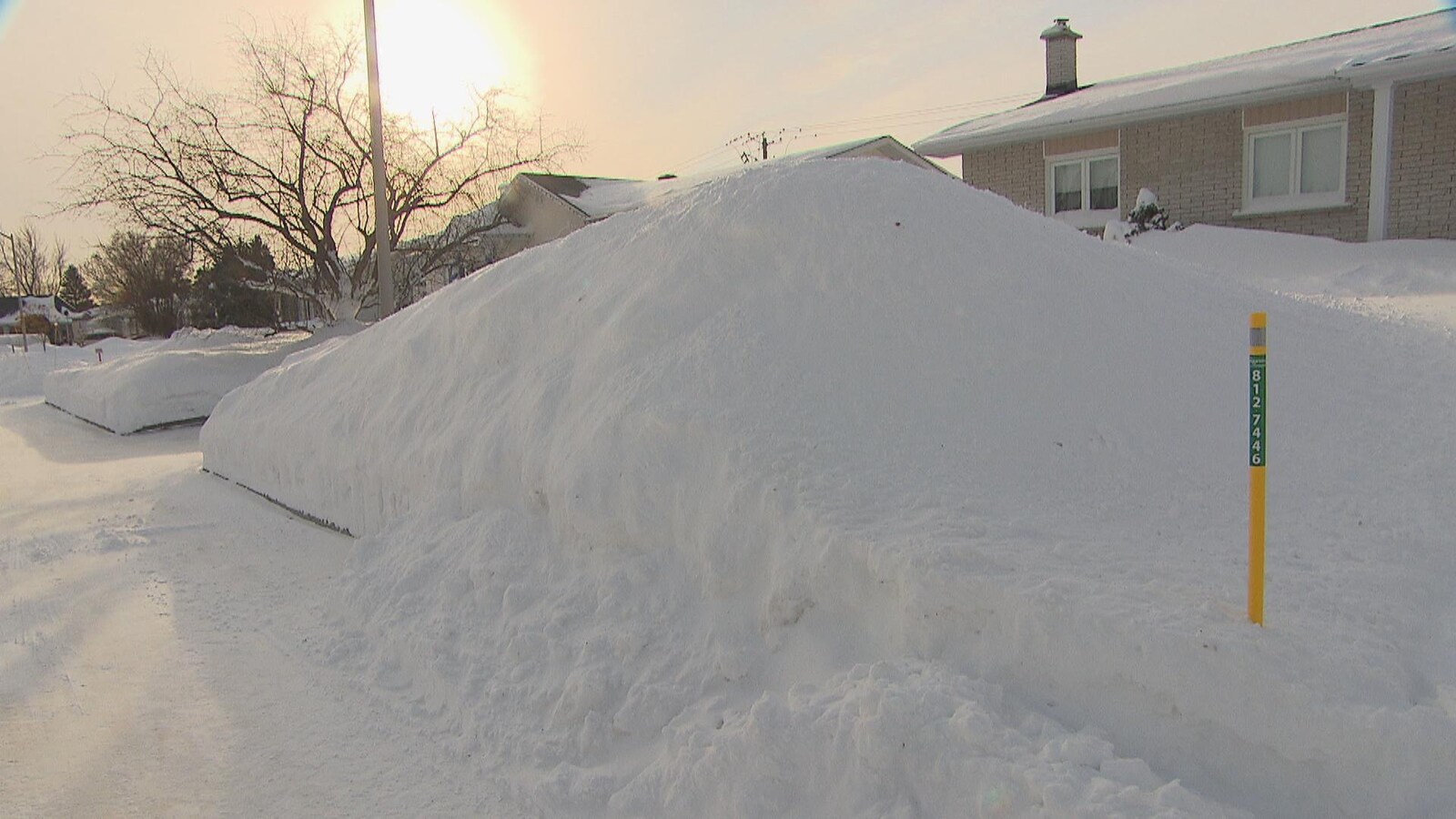 Un important banc de neige devant une maison de Saguenay.