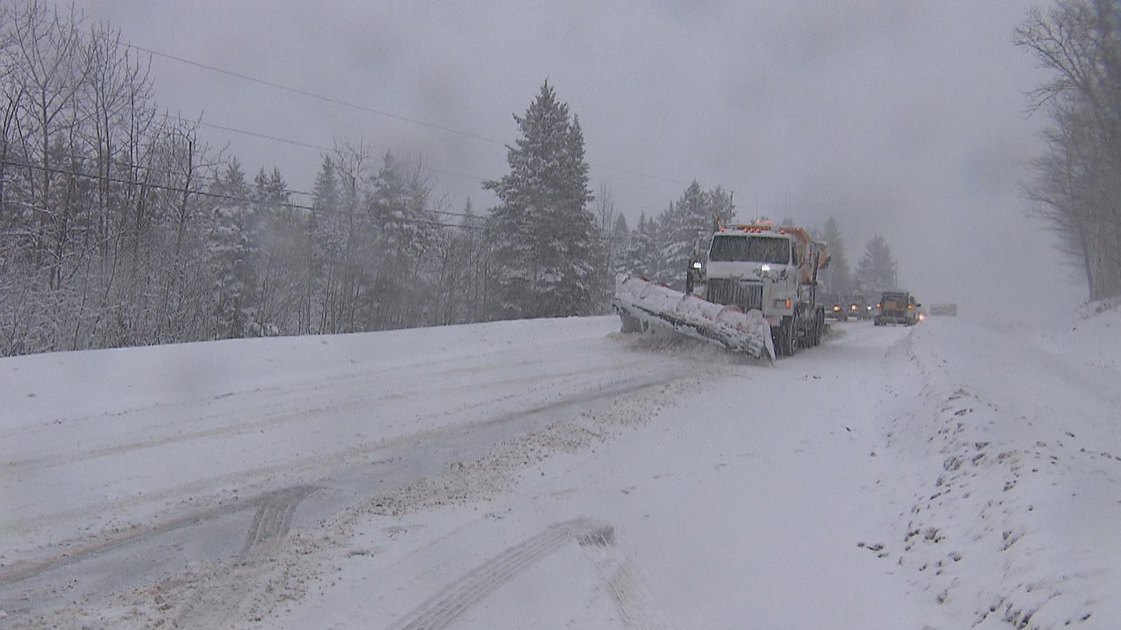 Un camion de déneigement circule sur la route 170 enneigée.