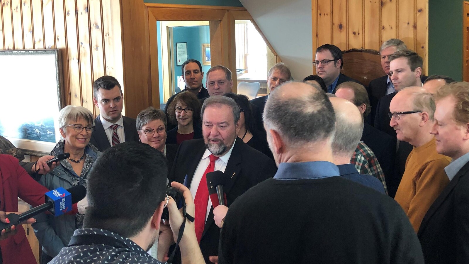 Denis Landry entouré des députés libéraux, dont Rob McKee, Cathy Rogers, Benoît Bourque et Brian Gallant, et des journalistes.