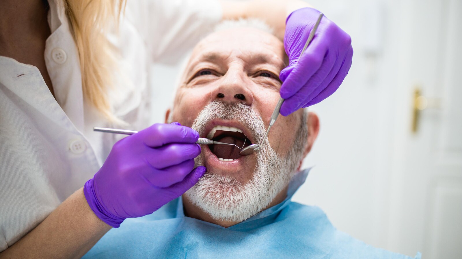 Homme d'un certain âge sur la chaise du dentiste, la bouche ouverte.