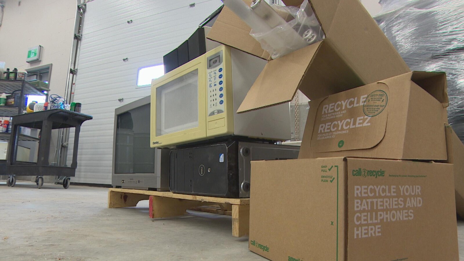 Une pile d'articles à recycler : un vieux microonde, une télévision, un ordinateur, des piles, dans le centre 4R.