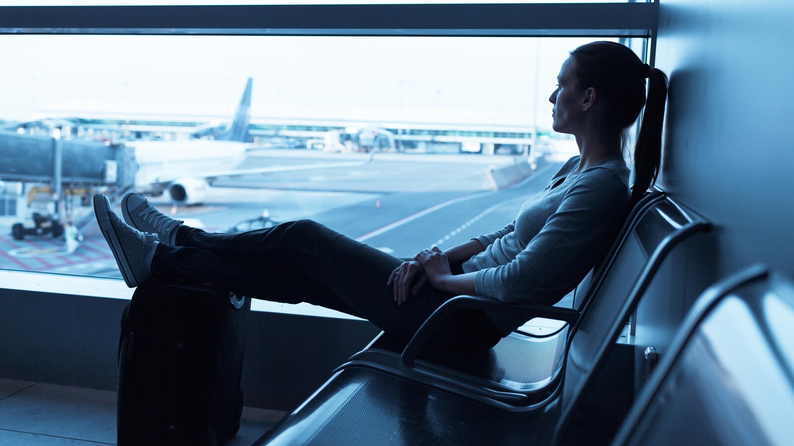 Une femme regarde à travers la fenêtre à l'aéroport