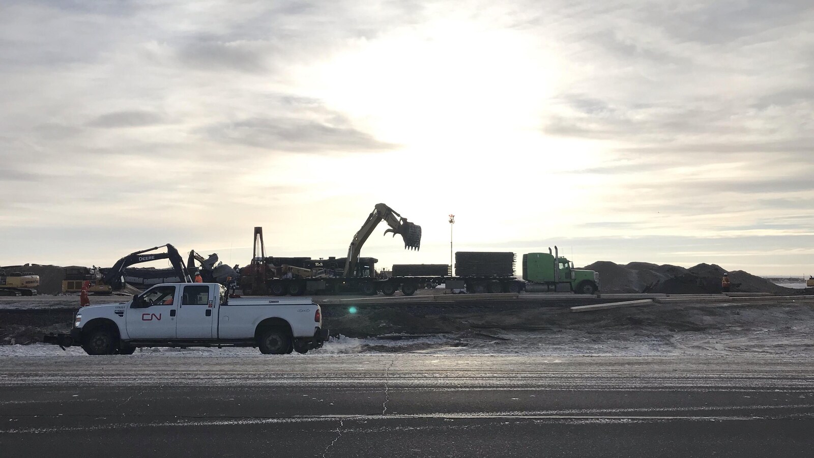 Une camionnette du CN sur une route, devant des wagons de train déraillés