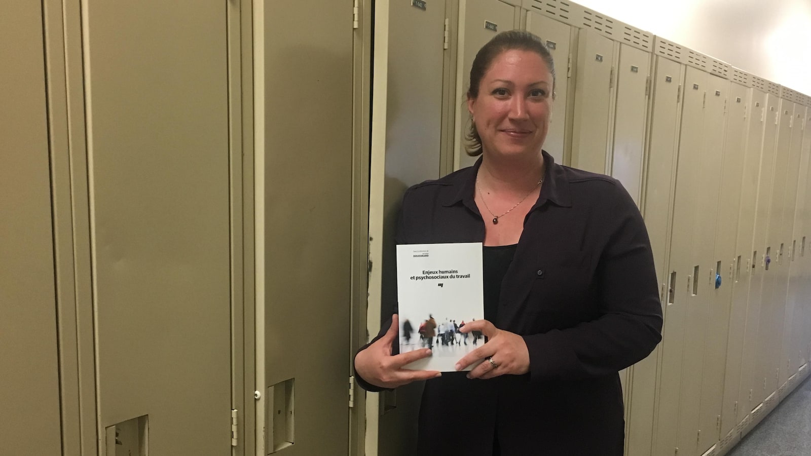 Jacinthe Douesnard pose avec son livre dans un corridor de l'université