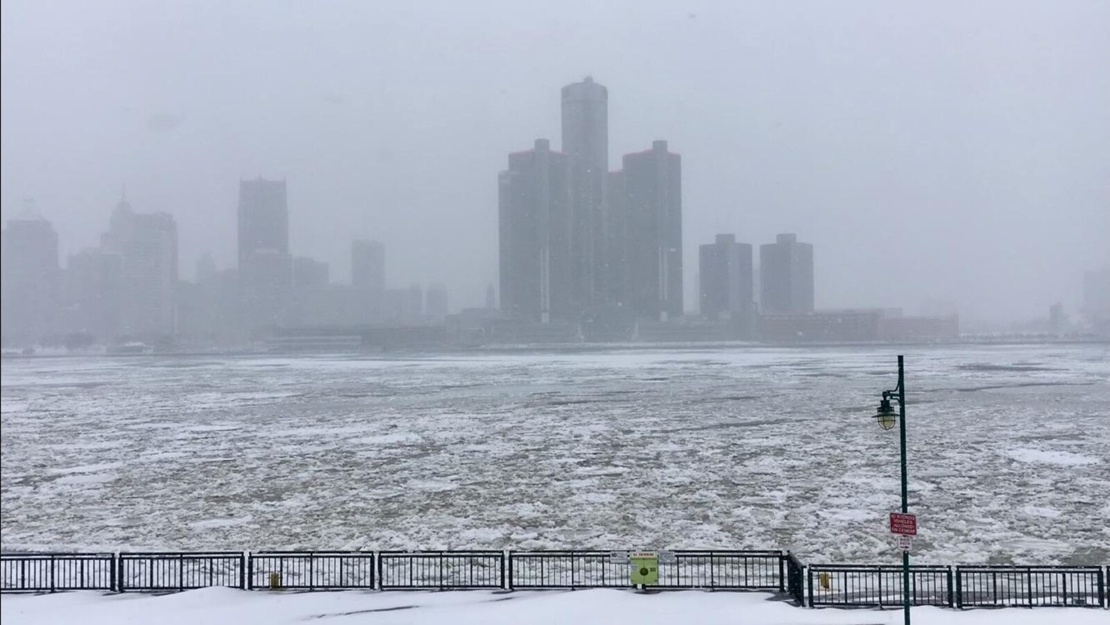 Rivière en partie glacée et centre-ville sous la neige.