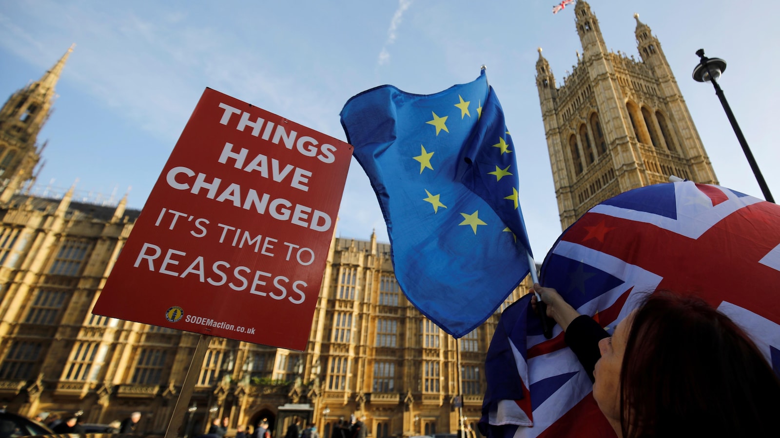 « Les choses ont changé. Il est temps de réévaluer », peut-on lire sur une pancarte installée devant le Parlement britannique, tout près d'une femme brandissant des drapeaux du Royaume-Uni et de l'Union européenne.