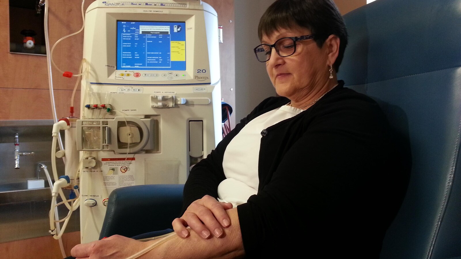 Une personne assise dont le sang est transféré à une machine de dialyse.