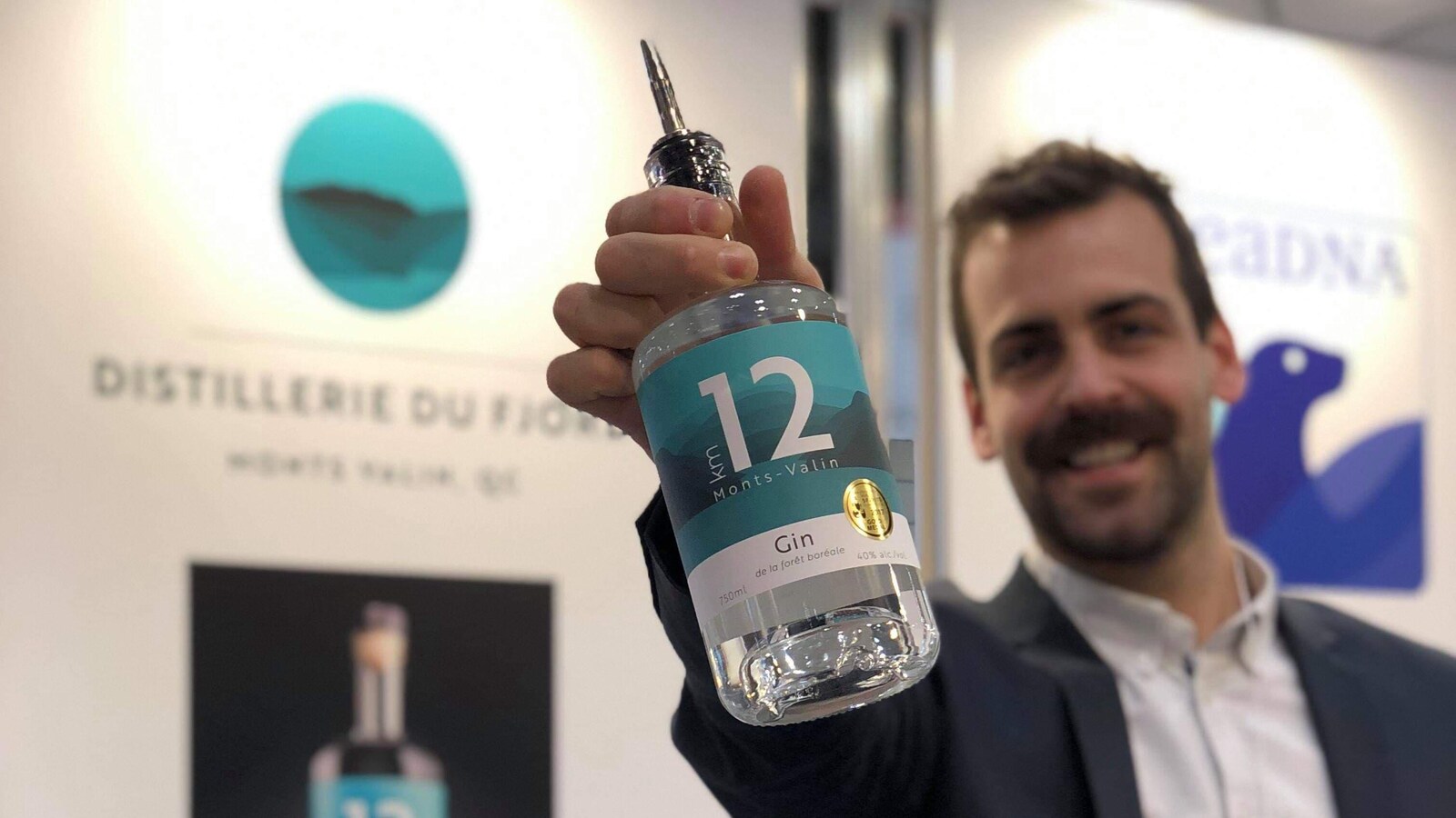 Un homme montre une bouteille de gin.