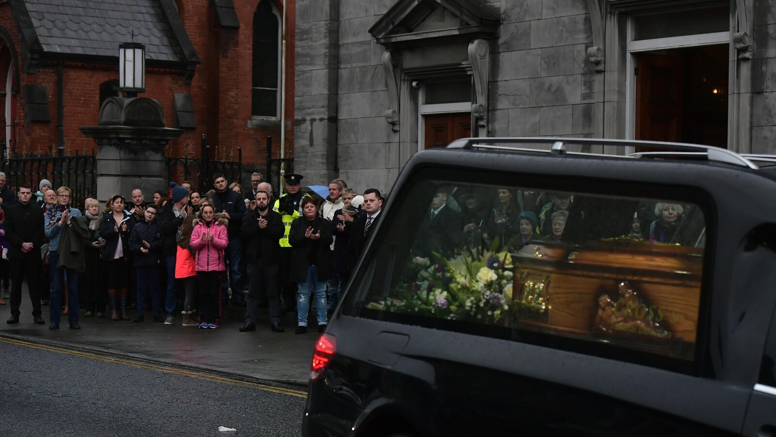 Des personnes applaudissent alors que le cercueil de Dolores O'Riordan quitte l'église Saint-Joseph de Limerick, en Irlande, le dimanche 21 janvier 2018.
