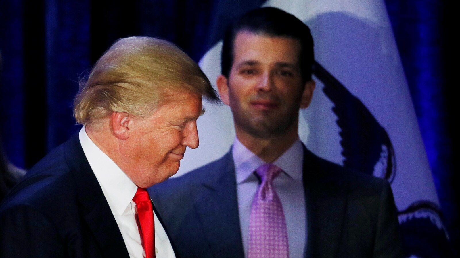 Donald Trump souri alors que son fils aîné se tient derrière lui.