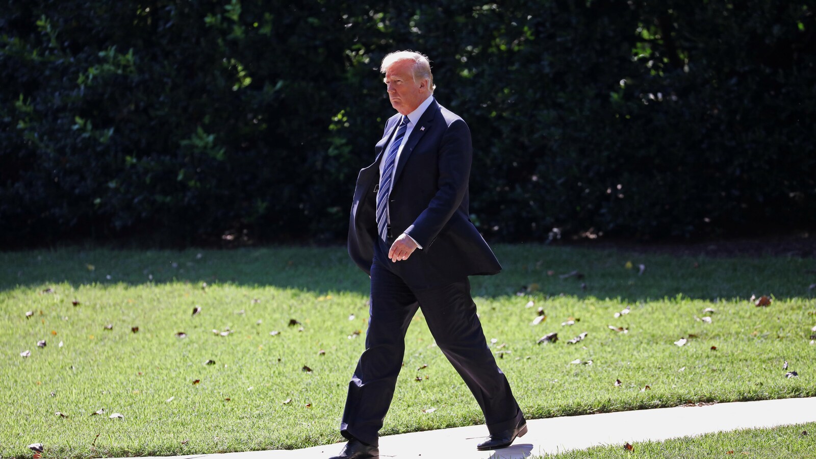 Donald Trump marche sur un terrain gazonné.