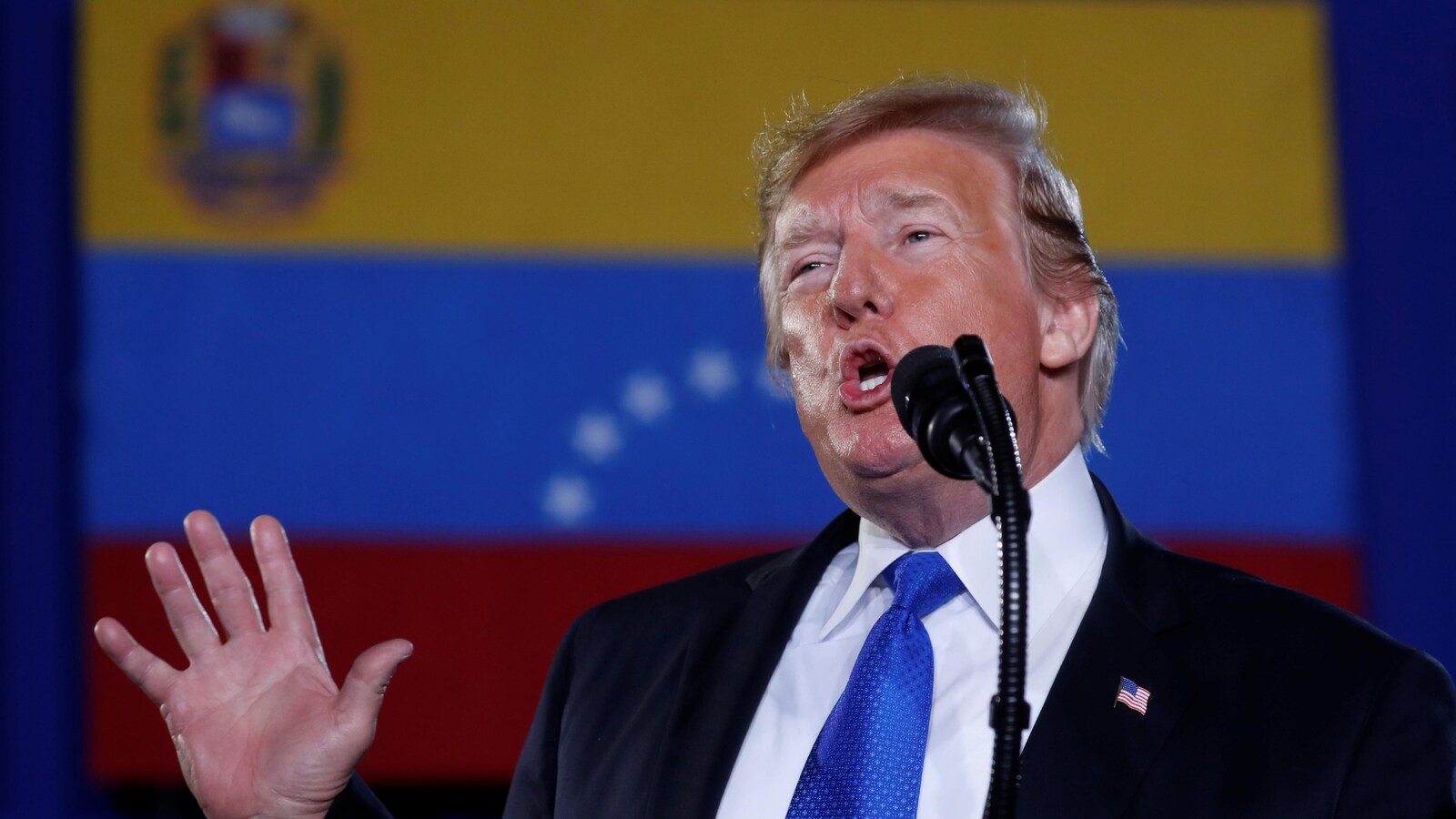 Donald Trump en conférence de presse, devant un drapeau vénézuélien.