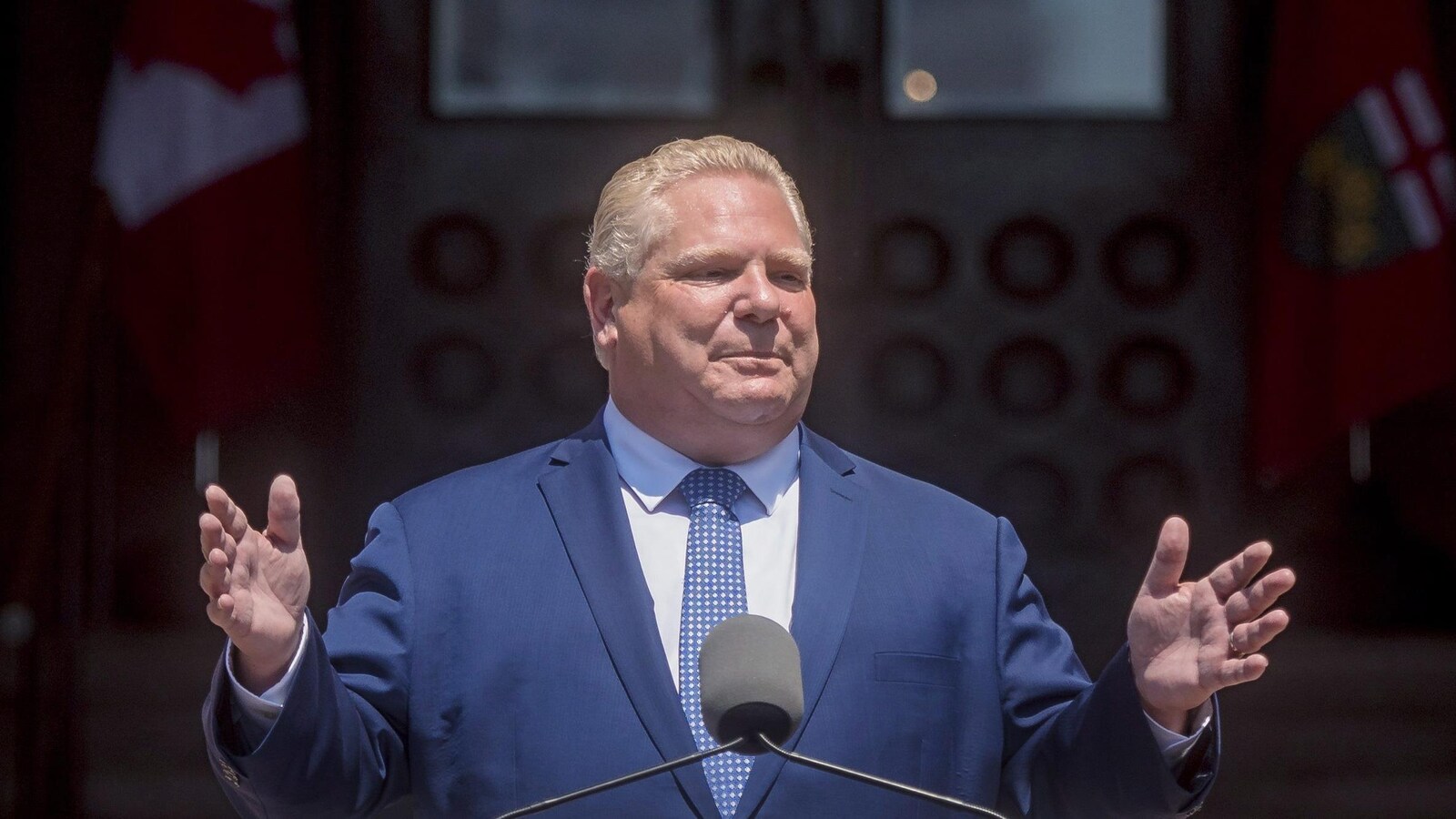 Doug Ford se tient les mains dans les airs devant un micro en s'adressant à la foule.