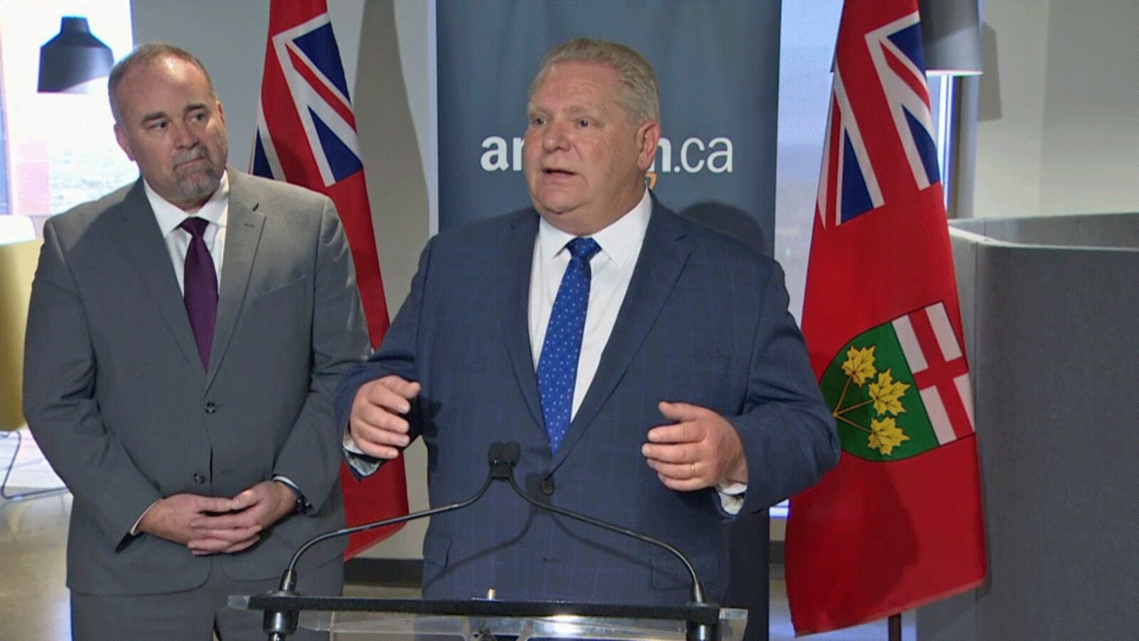 Photo d'un homme en complet bleu derrière un podium.