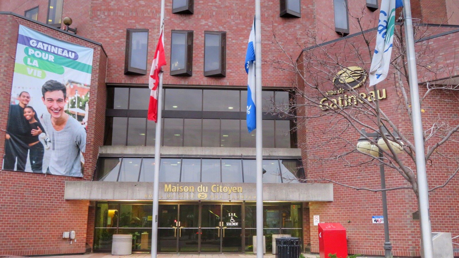 Les drapeaux de la Ville de Gatineau, du Québec et du Canada en berne devant la Maison du citoyen.