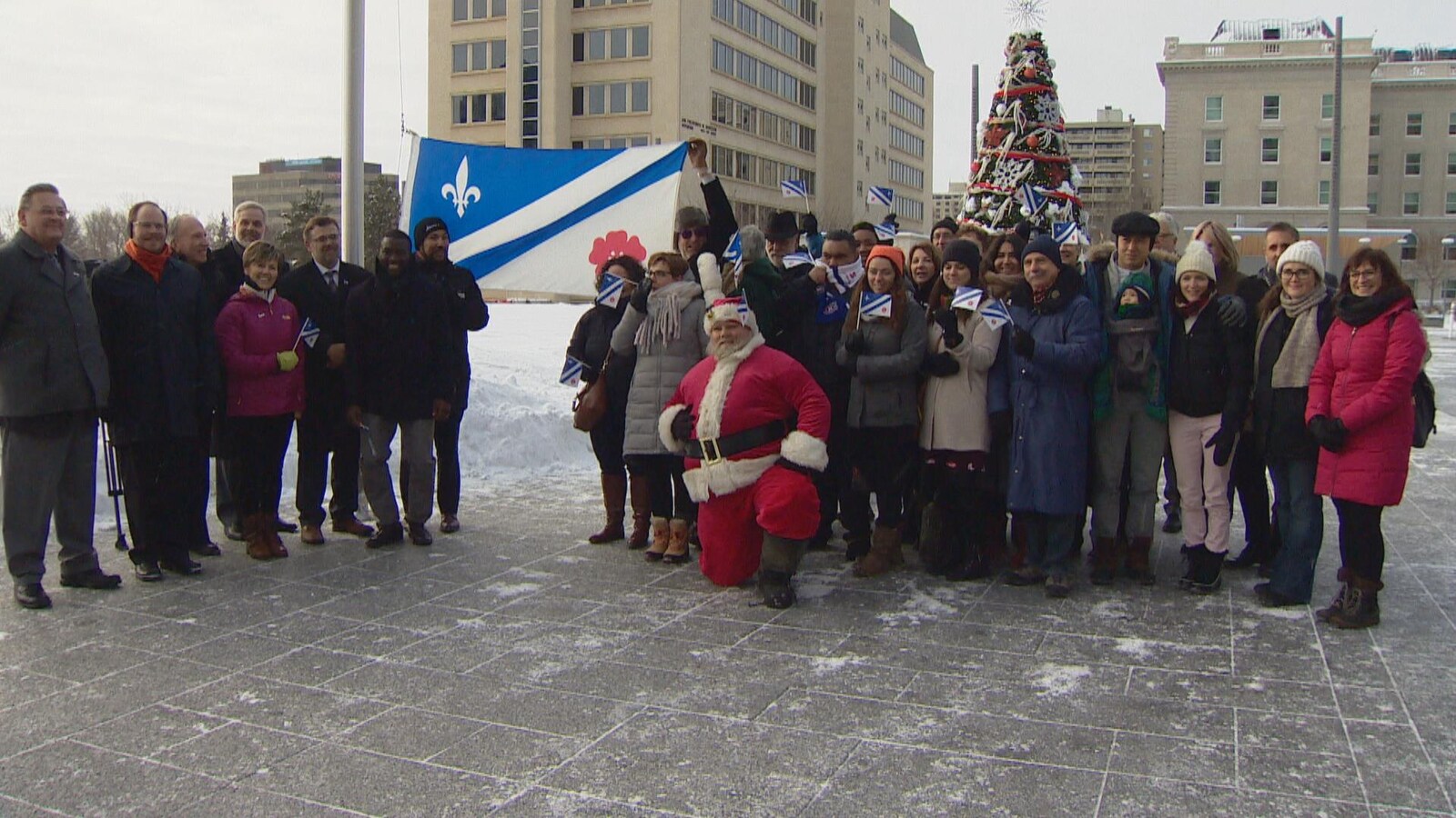 Une trentaine de personnes sont rassemblées devant le drapeau franco-albertain avant qu'il soit hissé sur un mat.