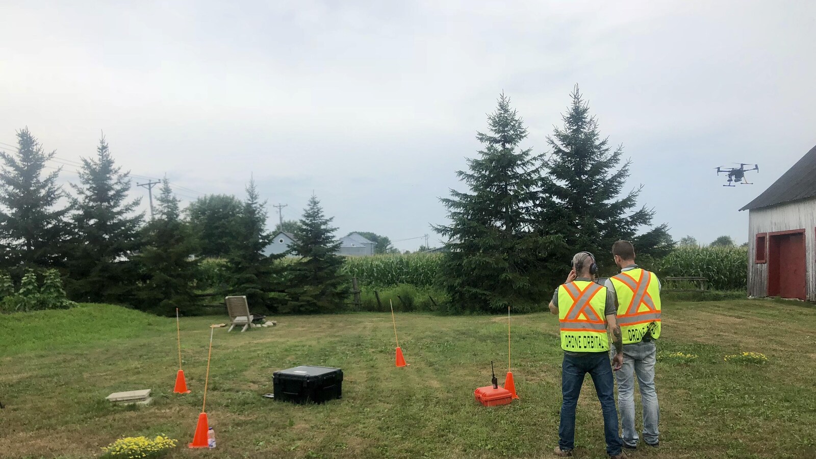 Deux hommes qui portent un dossard jaune fluo pilotent un drone.
