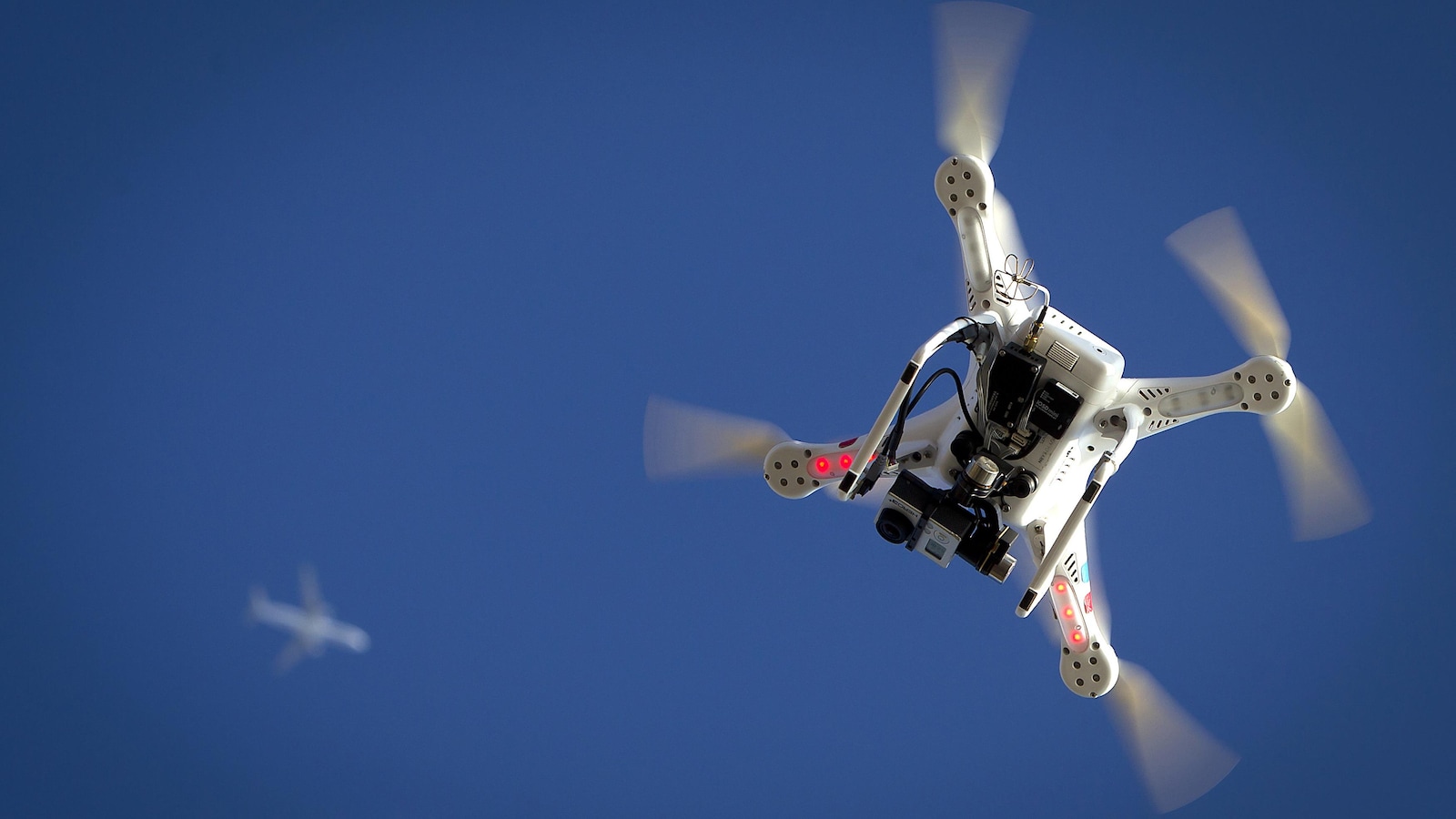 Un drone vole au dessous d'un avion.