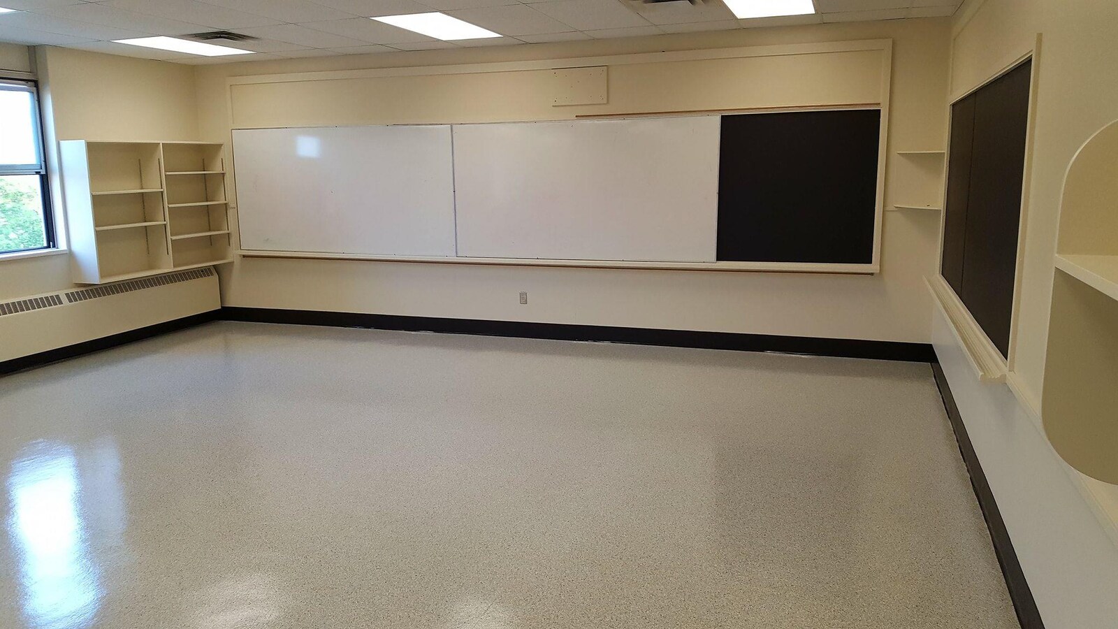 Une classe dans une école, avec des murs beiges et un tableau noir