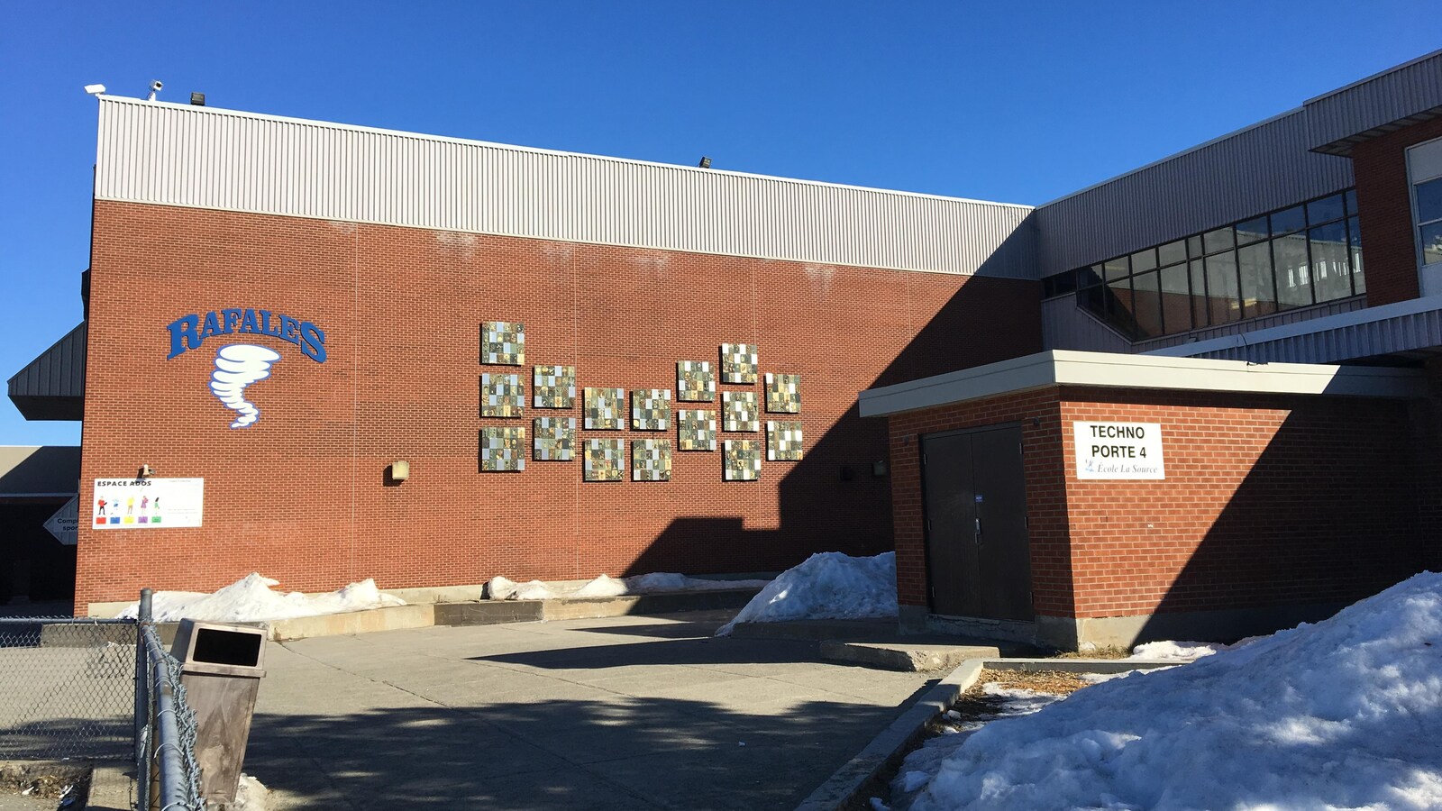 Une école secondaire avec le logo de l'équipe sportives «Les Rafales» sur un mur extérieur.