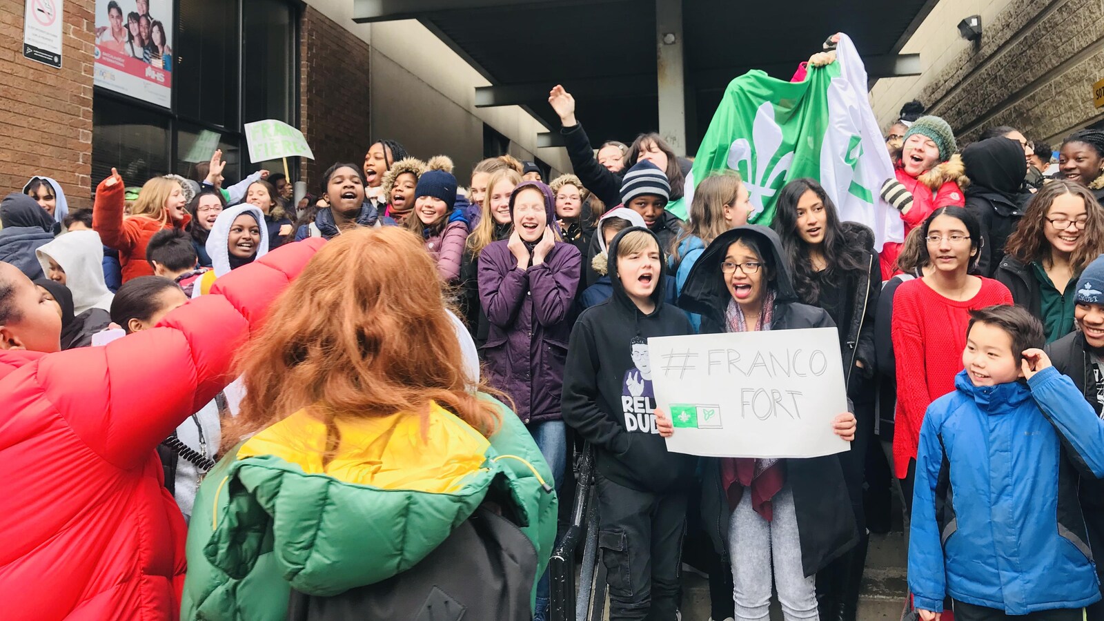 Photo d'élèves à l'extérieur tenant un drapeau franco-ontarien et une affiche qui dit « Francofort ».