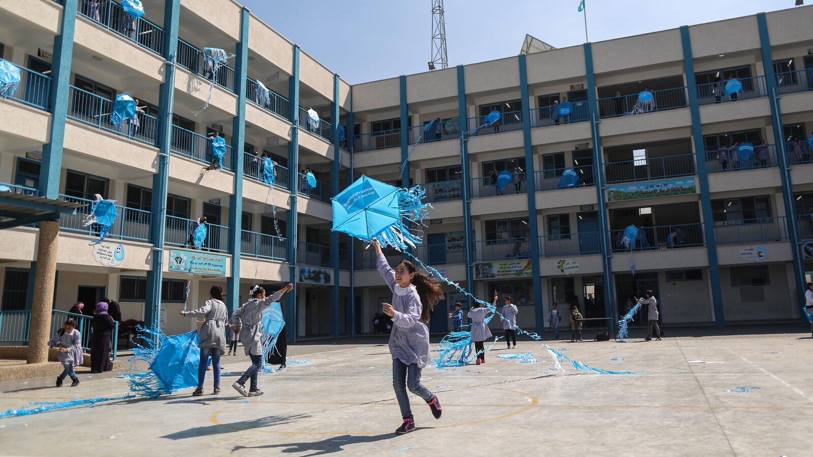 De jeunes filles s'amusent avec des articles promotionnels de l'UNRWA dans une cour d'école.