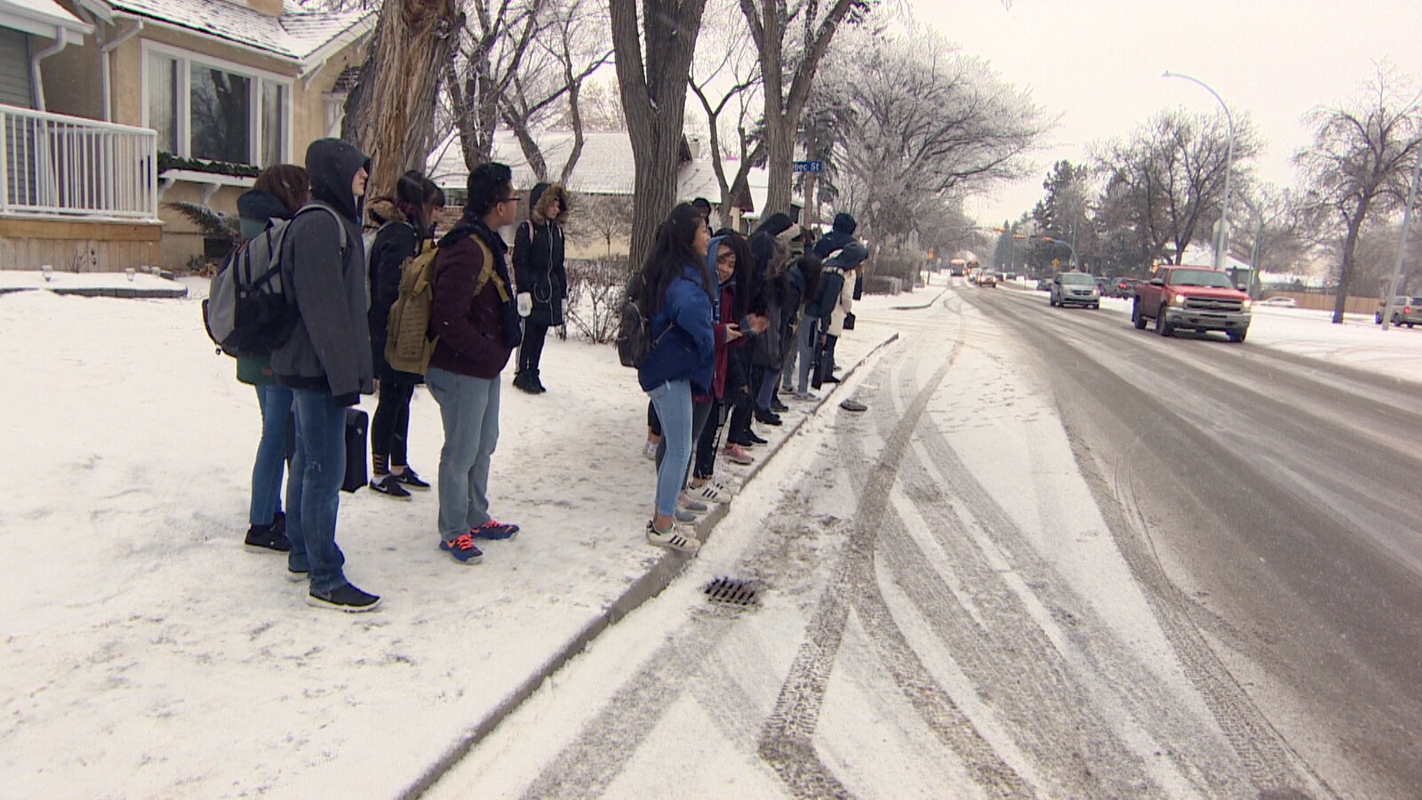 Des jeunes sur le bord de la rue qui semblent attendre l'autobus.
