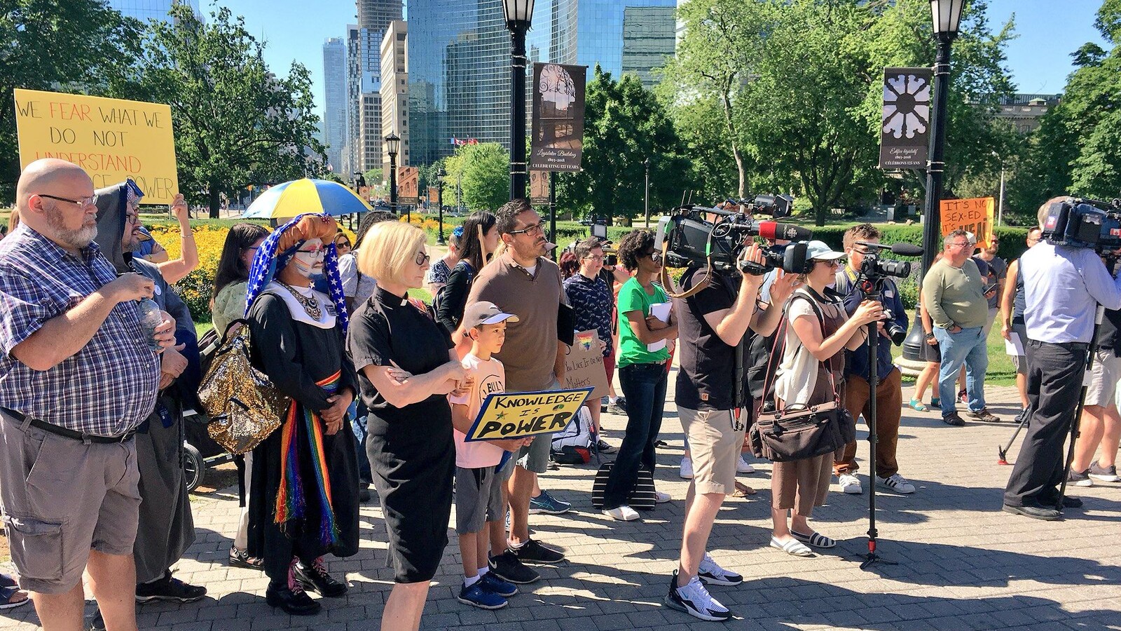 un groupe de personne portant des pancartes rassemblées devant Queen's Park.