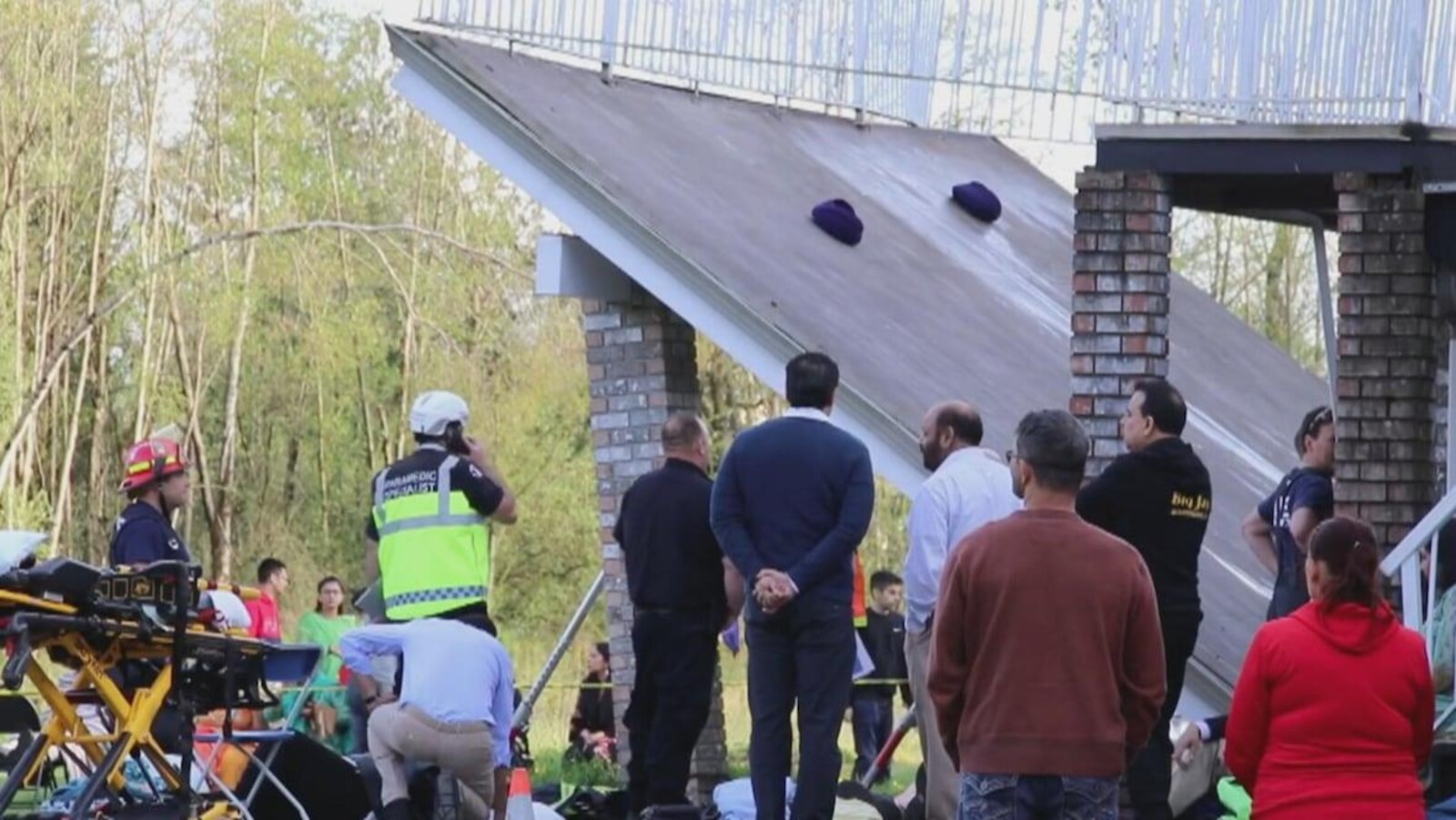 Une terrasse touche le sol, contemplée par une dizaine de personnes, dont un policier et un membre de l'équipe des secours.