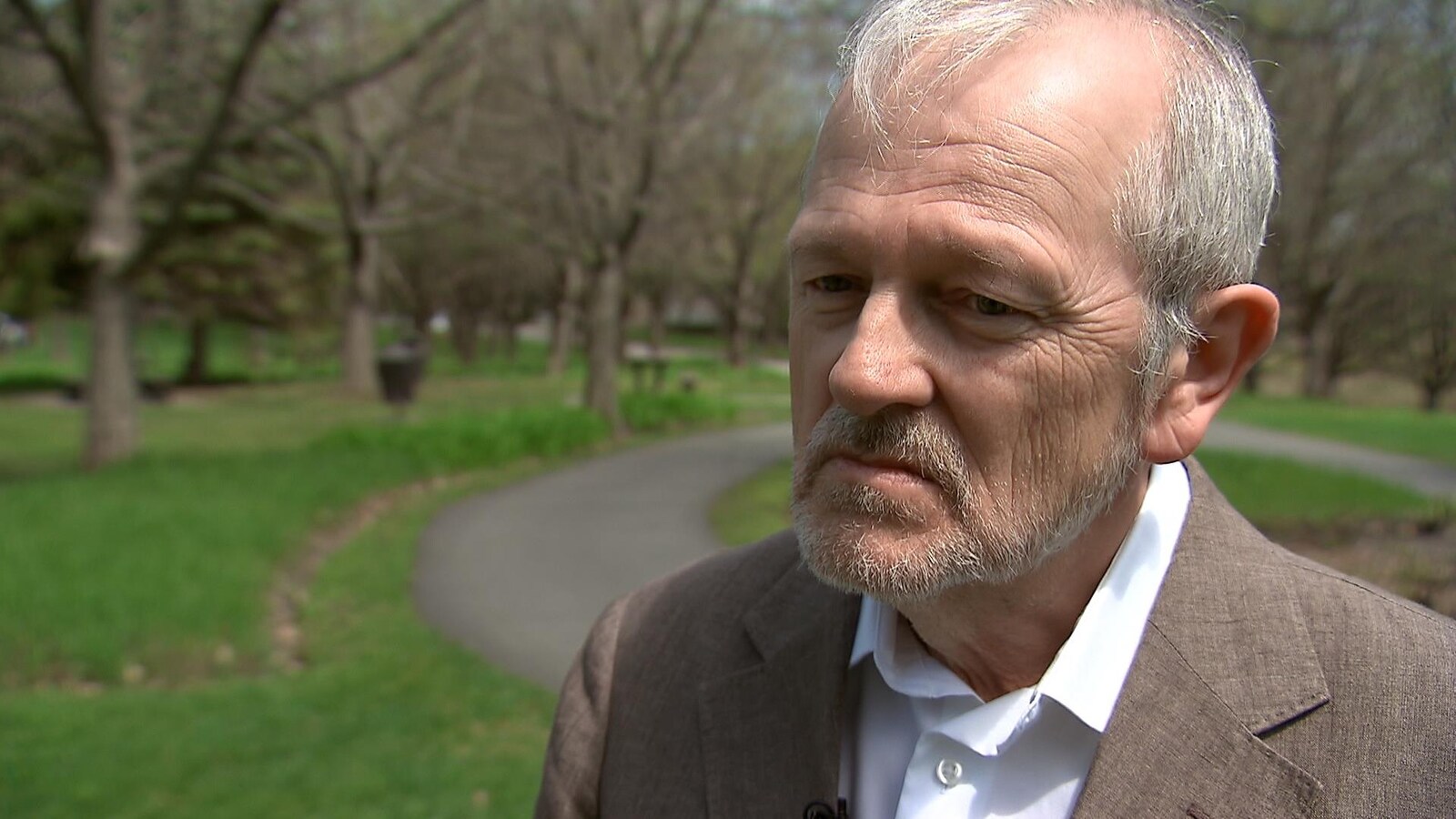 Un homme répond aux questions d'un journaliste dans un parc.