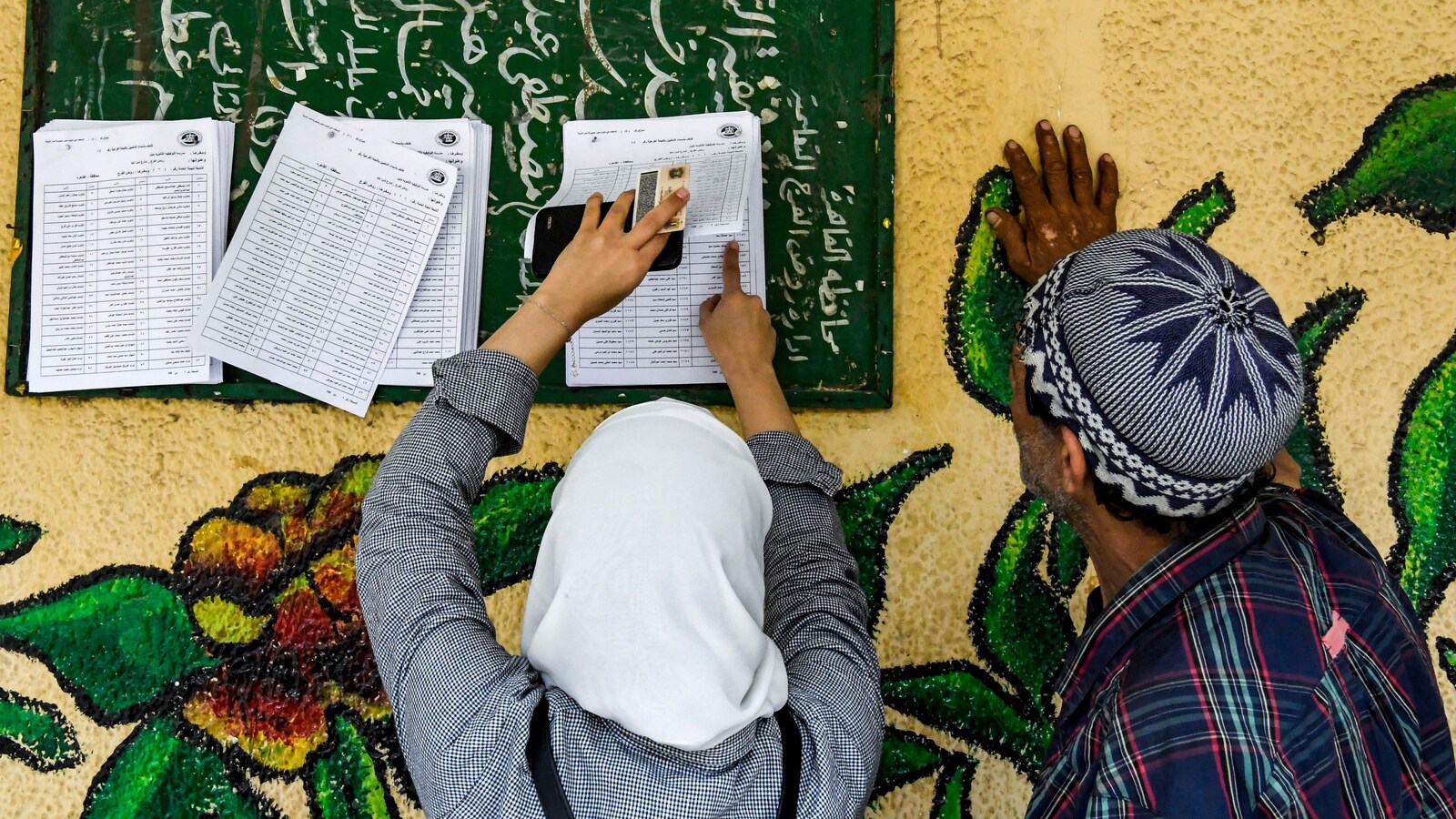 Un Égyptien et une Égyptienne sont à la recherche du bureau de vote où ils pourront remplir le bulletin de vote, dans le nord du Caire, au premier jour d'un scrutin de trois jours.