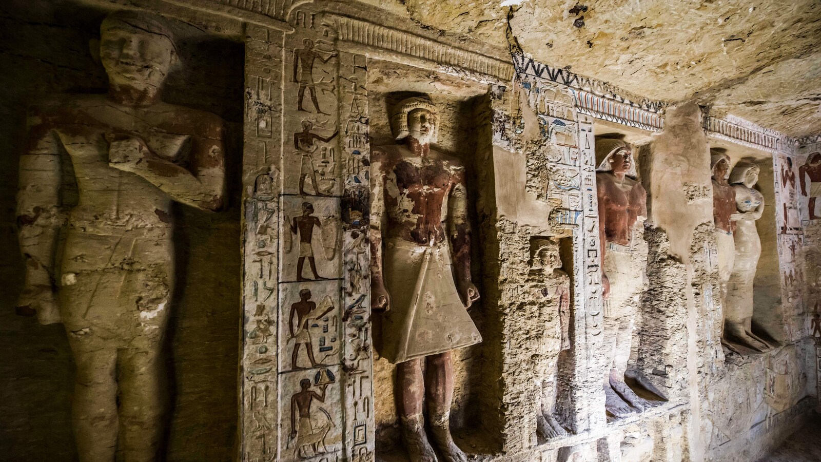 Des figurines sont taillées dans un mur de pierre.