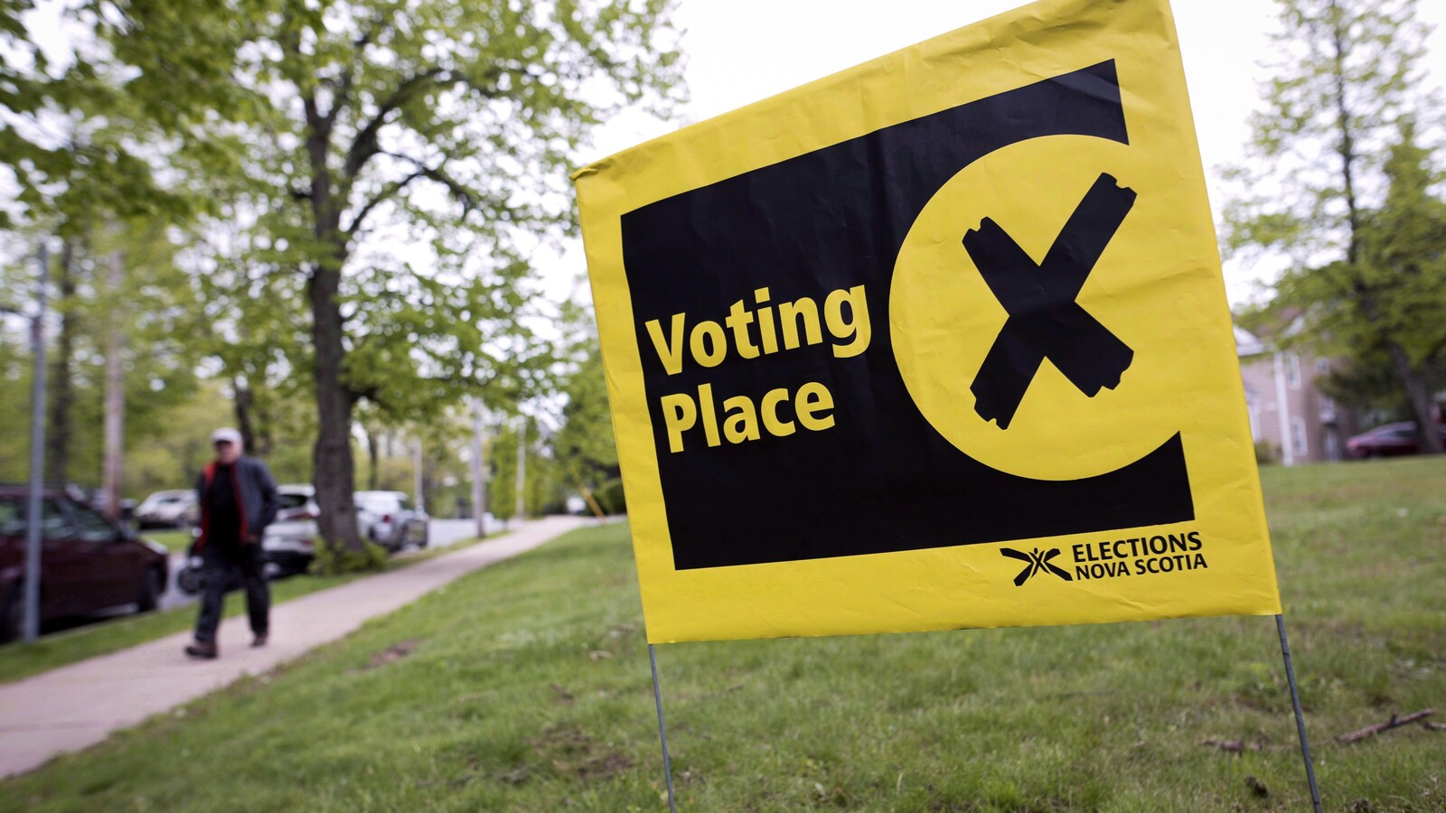 Petit drapeau jaune et noir planté dans la pelouse annonçant la proximité d'un bureau de vote en Nouvelle-Écosse.