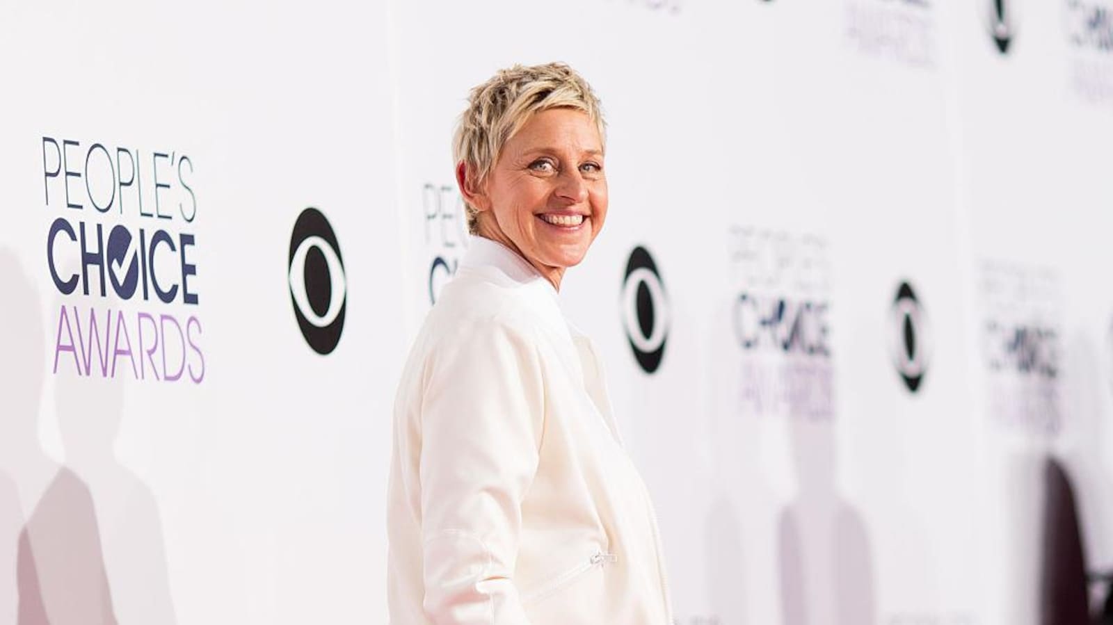 Ellen DeGeneres pose vêtue de blanc.