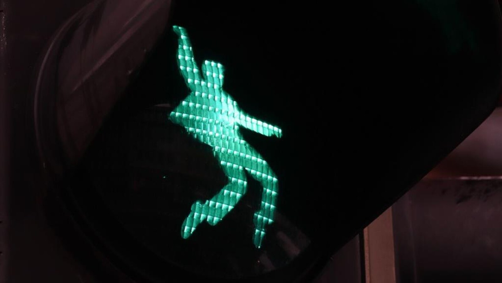 Un feu de signalisation avec une silhouette verte qui se déhanche.