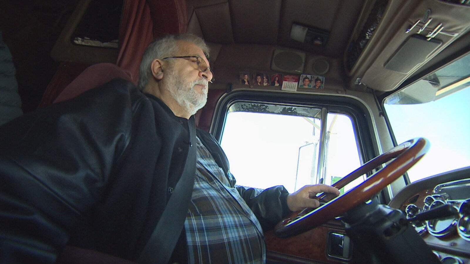Un homme photographié dans la cabine d'un semi-remorque.