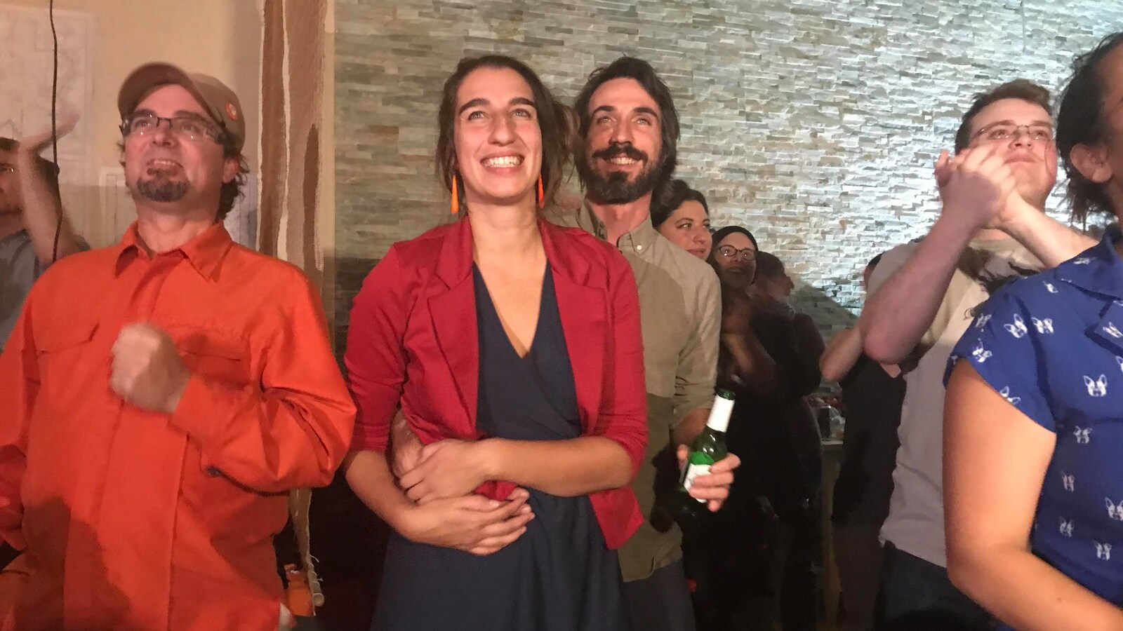 Émilise Lessard-Therrien est enlacée par son conjoint et sourit en regardant les résultats.